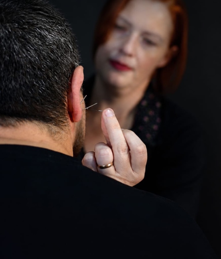 Aplicação de agulha de auriculoterapia na orelha de um paciente
